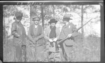 George Eastman holding rifle, with three women, Oak Lodge Trip