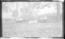 George Eastman and guests sitting by rail fence, Oak Lodge Trip