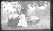 Guests on bench under large tree, Oak Lodge Trip