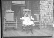 Two girls in rocker on porch, Oak Lodge Trip