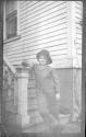 Girl leaning on bannister in front of house