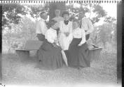 George Eastman and Oak Lodge guests sitting on bench around tree