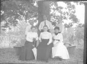 George Eastman and Oak Lodge guests sitting on bench around tree