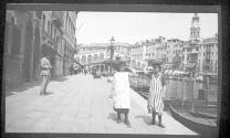 [Women along canal, cityscape distant]