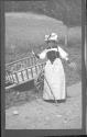 [Woman in native dress by wooden cart]