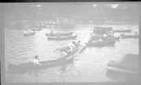 [People in rowboats & canoes on lake]