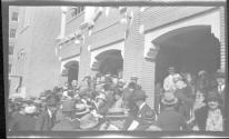[Group of people on steps of large brick building]