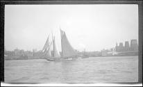 [Sailboat on river, city skyline in distance]