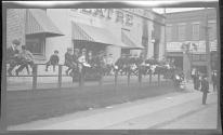 [Group of boys on railing along street]