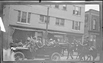 [People in automobile followed by mounted policemen]