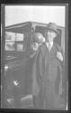 [Man by automobile holding grapefruit]