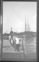 [Group of children on dock, sailing ship in background]