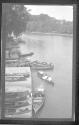 [People & canoes at dock along river]
