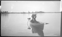 [Man in boat with camera on tripod in water]