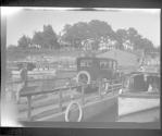[Automobile on small ferry boat on river with other boats]