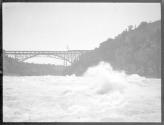 [View of river rapids, bridge in distance]