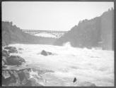 [View of river rapids, bridge in distance]