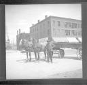 Man standing next to horse drawn cart on street