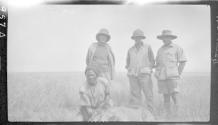 Three men with guide posing around dead lion, African Safari