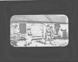 Men with guns in front of farm workers' house, Oak Lodge Trip