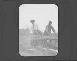 Woman helping man cut wood, Oak Lodge Trip