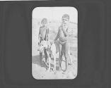 Two native boys with painted faces and a dog