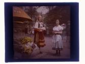[Two women in folk dress selling flowers]