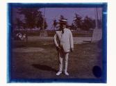 [Man standing in park in white suit]