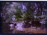[Two men in canoes along river]