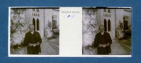 [Man in front of house holding paper]