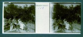 [Unid. woman and two men on terrace backed by gardens]