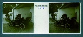 [Unid. man standing in courtyard by car]