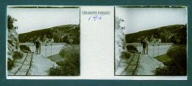 [Man posing on cliff by tracks with dam in backround]
