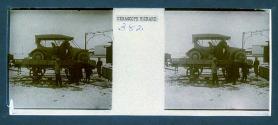 [Men next to auto on top of train flat bed]