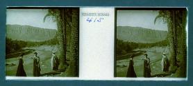 [Two women and guide next to stream with mountains in backround]