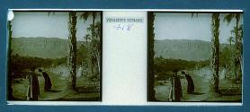 [Two women standing by stream, town in backround]