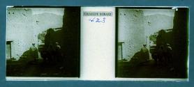 [Three people and mule in dirt alley]