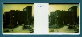 [Man pushing cart in front of old stone building]