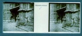[Unid. woman standing by stone architecture]