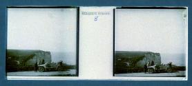 [Three unid. people next to car on hill overlooking water]