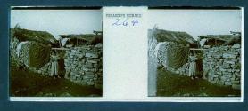 [Woman holding child in doorway of building made of piled stones]