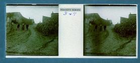 [Tourists walking on dirt road flanked by stone buildings]