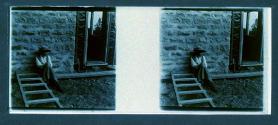 [Woman seated by side of building]