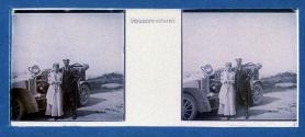 [Unid. woman and man standing by car]