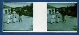 [Two unid. women and Arab(?) man in courtyard]