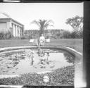 Dryden child sitting by pond, East garden
