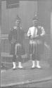 [Two men wearing kilts]