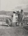 [Men pouring water into barrel]