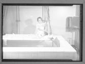 [Woman Lowering Child into Therapy Bath]