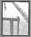 Setting a beam two men perched at top of I beam